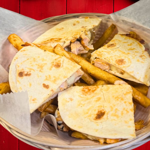 Chicken quesadillas with melted cheese and french fries in a basket from The Gordito Tacos.