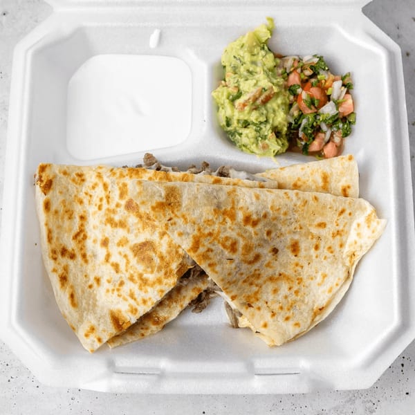 A Gordito Tacos quesadilla with guacamole, pico de gallo, and sour cream in a takeout container.