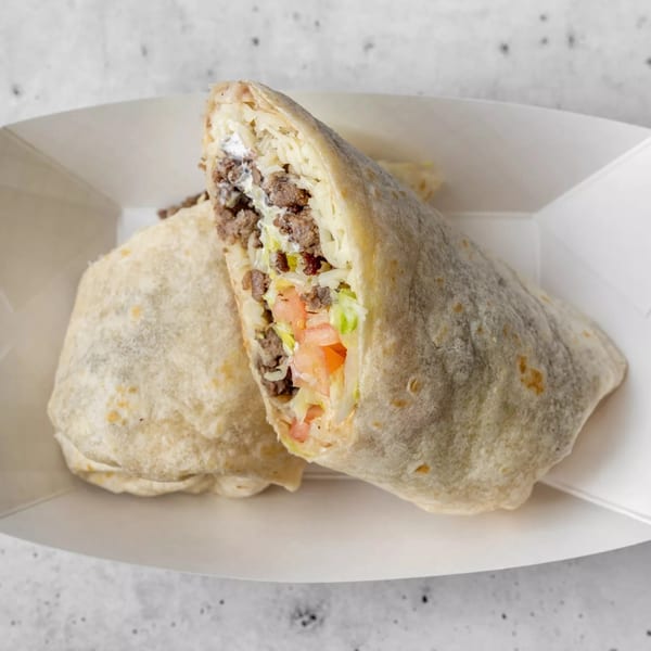 Two Gordito Tacos burritos, one cut in half, revealing ground beef, lettuce, tomato, and sour cream.