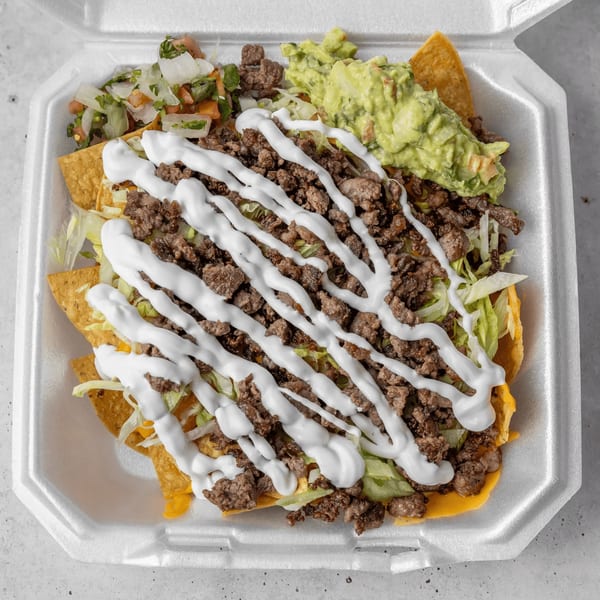A takeout container of Gordito Tacos nachos with ground beef, lettuce, sour cream, guacamole, and pico de gallo.