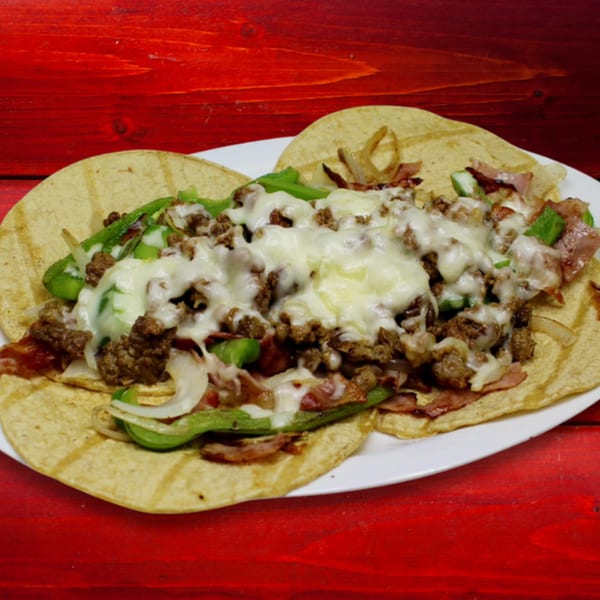 Three Gordito Tacos with ground beef, melted cheese, peppers, onions, and bacon on a white plate.