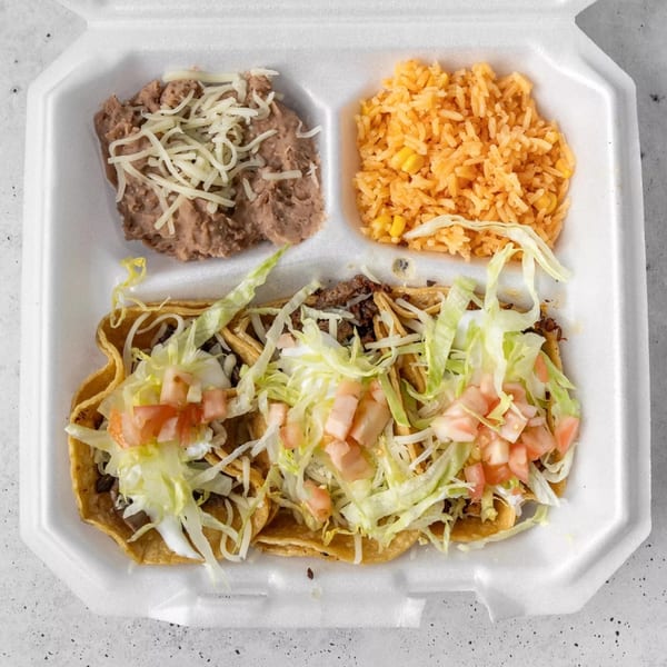Three Gordito Tacos with shredded lettuce, diced tomatoes, rice, and refried beans in a takeout container.